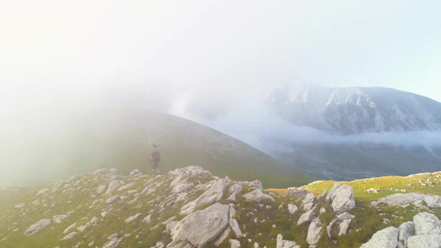 在日落时分，一名年轻人在意大利阿布鲁佐山的山脊边缘徒步旅行视频素材