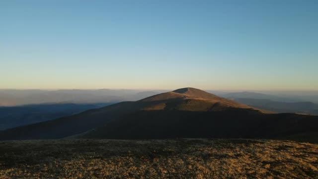 在日落时飞过那座山。日落时的山脊全景鸟瞰图。夏日的自然背景与温暖的阳光视频素材