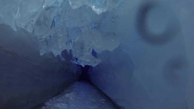 蓝色的冰洞覆盖着雪，充满了阳光。视频素材