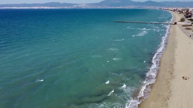 在希腊Agia Triada Thessaloniki地区，海浪和旅游建筑的海滩鸟瞰图，无人机向前移动视频素材