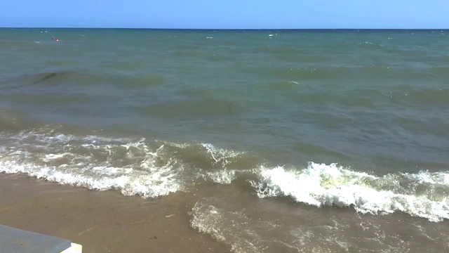 在希腊塞萨洛尼基地区，夏天有海浪和木制日光浴床的田园诗般的海滩视频下载