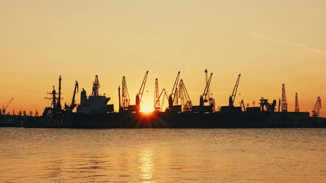 海上城市港口。海面平静的摇摆。一群海鸟、海鸥，在明亮的橙色夕阳背景下，盘旋在船只和起重机上视频素材