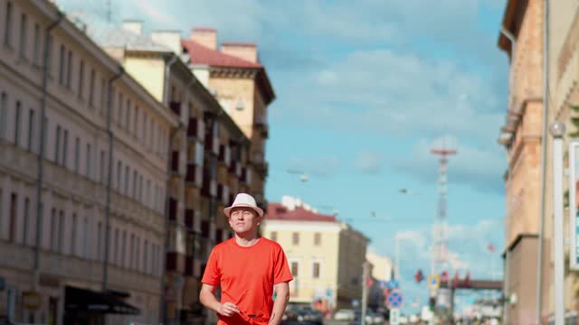 戴着白帽的年轻男游客走在城市街道上，摄像头跟踪着视频素材