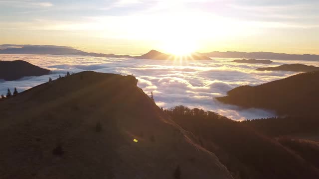 史诗全景鸟瞰日出与雾云的野生山在阳光山谷高山自然景观视频素材