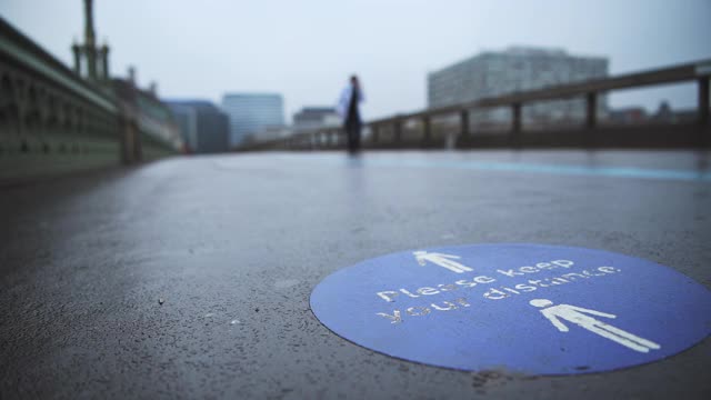 英国英国，在伦敦，街道空空荡荡，威斯敏斯特桥的道路寂静无声，为了保持社交距离，人行道上的Covid-19封锁信息标志保持社交距离视频素材