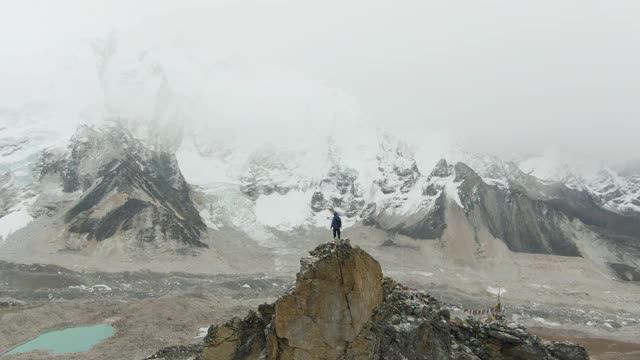 卡拉帕塔山顶上的徒步旅行者。昆布冰瀑、珠穆朗玛峰大本营、Nuptse和Pumori山。尼泊尔的喜马拉雅山脉。鸟瞰图。无人机是轨道视频素材