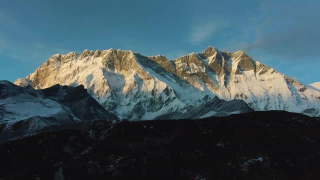 粉色日落时分的Nuptse山和Lhotse南脸。尼泊尔的喜马拉雅山脉。鸟瞰图。无人机横向向上飞行视频素材