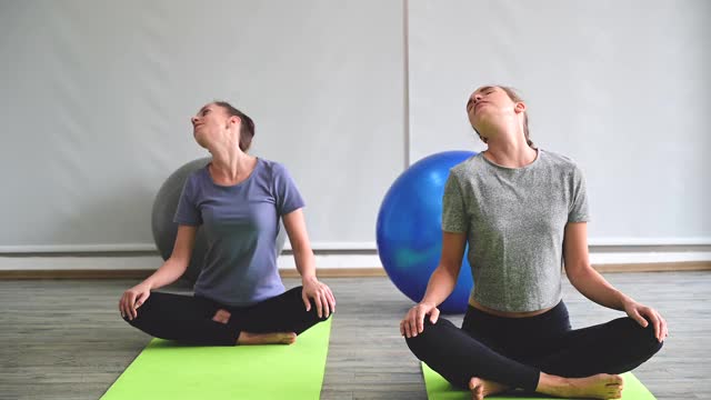 一对健康的年轻白种女性穿着运动服在家里做瑜伽练习。视频素材