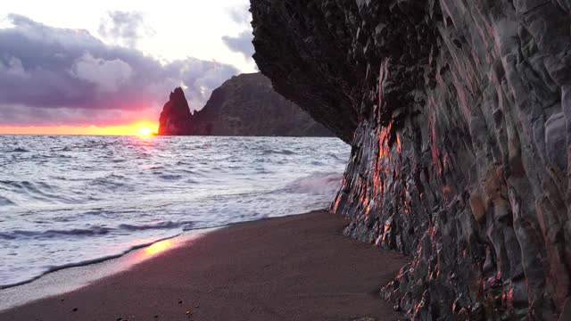 彩色温暖的日落在海上和火山玄武岩，就像在冰岛。海浪撞击着岩石，在温暖的夕阳照耀下溅起白色的泡沫。大自然永无止境的美丽视频素材