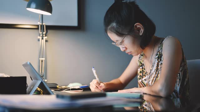 亚洲少女戴着耳机坐在笔记本电脑前，参加在线视频教室与老师在她的卧室视频素材