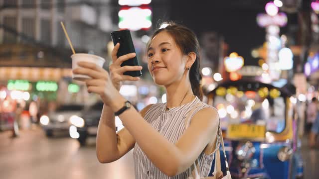 在泰国曼谷唐人街的瑶华路，当地的亚洲女游客喜欢在晚上吃冰淇淋和自拍视频素材