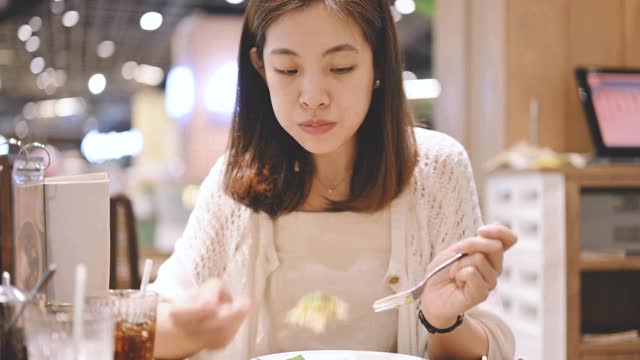 年轻的亚洲女子在餐厅用餐时看着镜头。美丽的亚洲女孩在餐厅微笑视频素材