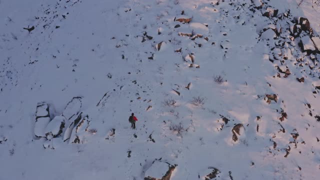 无人驾驶飞机飞过雪地里爬山的人视频素材