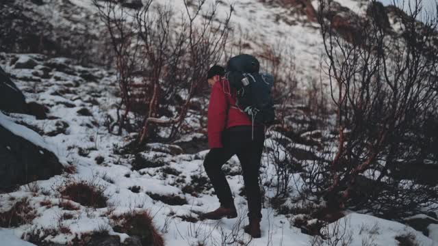 一个人爬上白雪覆盖的山丘视频素材