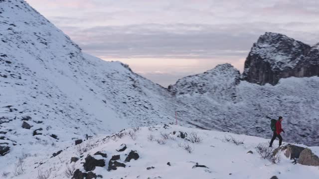 无人机盘旋在雪山小径上坚定的徒步者视频素材