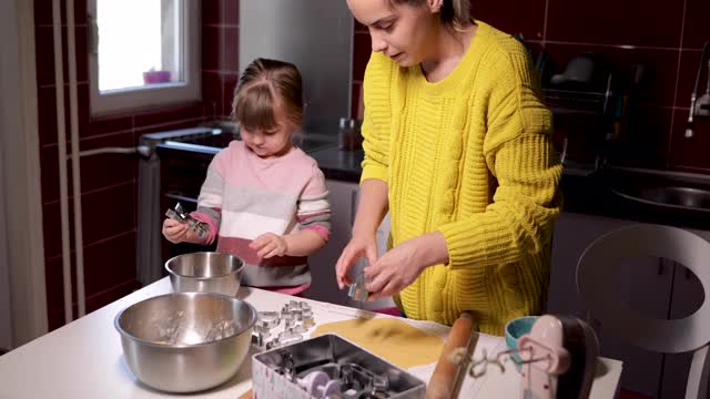 可爱的小女孩在家里和妈妈一起装饰饼干视频素材