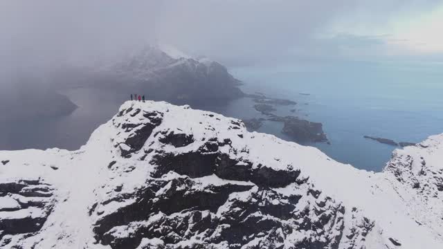 无人机飞越雪山山顶上的徒步旅行者视频素材