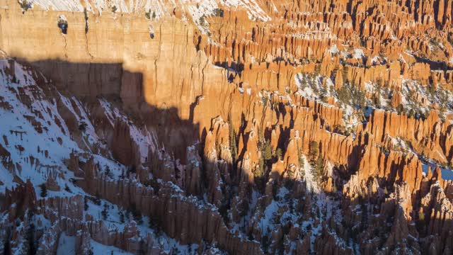 布莱斯峡谷hoodoo在冬天日出在阳光明媚的早晨。雪。布莱斯峡谷国家公园。美国犹他州。移动平移时间推移视频素材