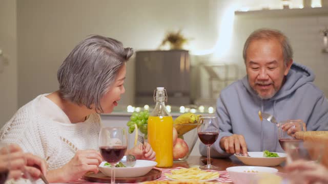 幸福的家庭时间和关系，亚洲大家庭有一个小聚会，一起在家里吃东西。爷爷很高兴看到他的孩子和侄子在家里的餐桌上吃饭，分享食物。视频素材