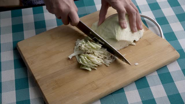 一个妇女在厨房的木板上切下一个新鲜的生卷心菜头。健康饮食的概念。关闭了。从上往下看。4 k决议。视频素材