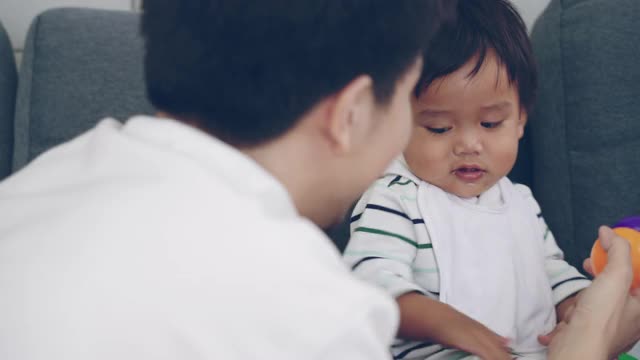 亚洲父母和男婴在家里的客厅玩塑料球视频素材