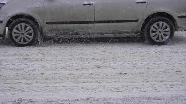 汽车在城市积雪的路上行驶，用的是冬季轮胎。冬季道路安全理念，拷贝空间，慢动作视频素材