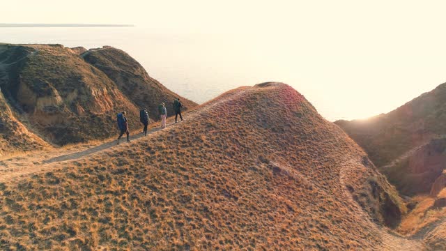 四个人走在山顶上，以美丽的大海为背景视频素材