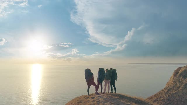 四位游客站在山崖上，背对着美丽的海景视频素材