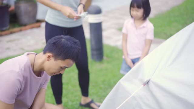 亚裔华人家庭在自家后院搭帐篷露营，进行周末度假活动视频素材