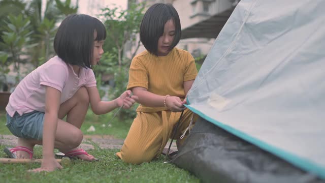 亚裔华人两姐妹在自家后院搭起帐篷，进行周末度假活动视频素材