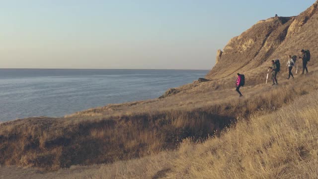 四名背包游客在海景背景上徒步旅行视频素材