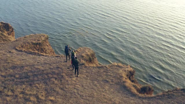 旅行者们背着背包在海边的沙岩顶上行走视频素材