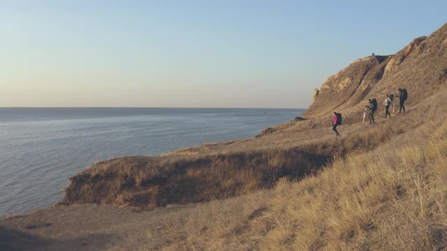 四名背包游客在海景背景上徒步旅行视频素材