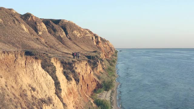 四个旅行者站在海边的沙岩上。Hyperlapse视频素材