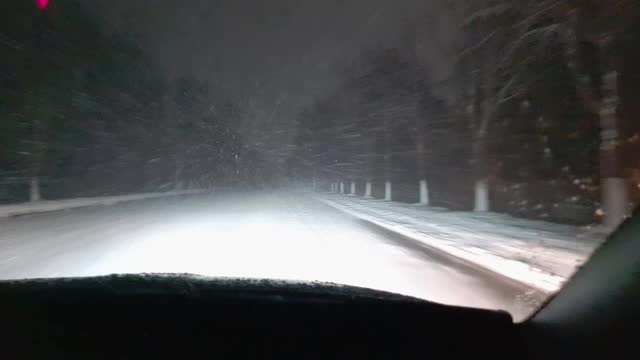 一辆在暴风雪中行驶的汽车的前挡风玻璃的内部视图。空的夜晚。视频素材