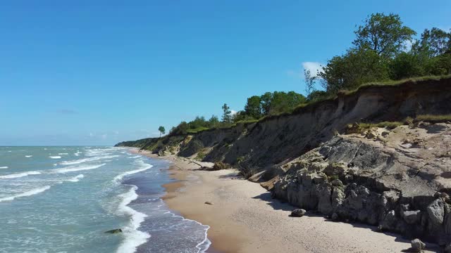 飞越海岸线波罗的海乌尔马莱海岸悬崖附近的Pavilosta，拉脱维亚和山体滑坡与一个杂草丛生的，波纹的洞穴点缀悬崖和鹅卵石。视频素材