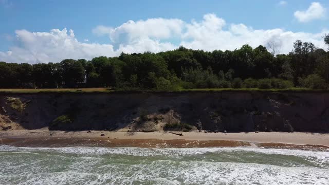 飞越海岸线波罗的海乌尔马莱海岸悬崖附近的Pavilosta，拉脱维亚和山体滑坡与一个杂草丛生的，波纹的洞穴点缀悬崖和鹅卵石。视频素材