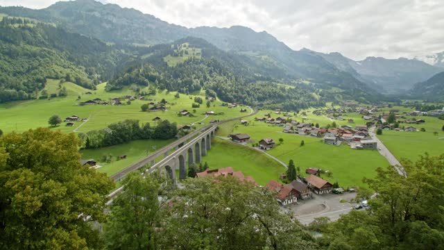 高架桥、村庄和山脉的延时全景。典型的瑞士住宅位于长满草的山谷中。Kandertal Frutigen。伯尔尼兹Oberland。广州伯尔尼。视频素材