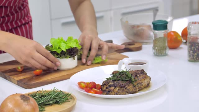 年轻的亚洲妇女在厨房做饭。视频素材