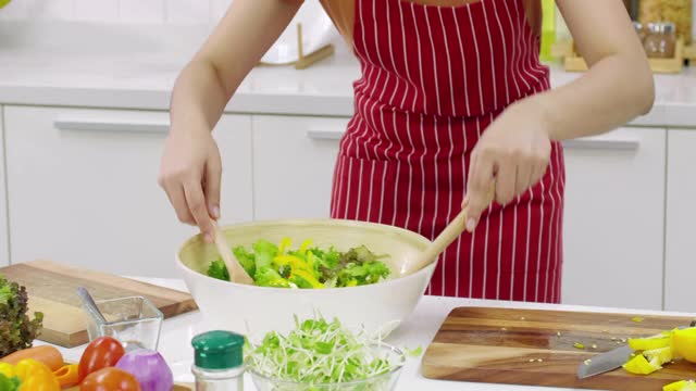 年轻的亚洲妇女在厨房做饭。视频素材