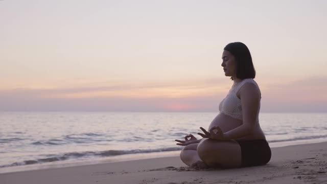 年轻的亚洲孕妇放松散步在海滩上日落视频素材