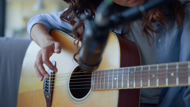 女孩的手指拨动着吉他弦。女子录制吉他声音视频素材