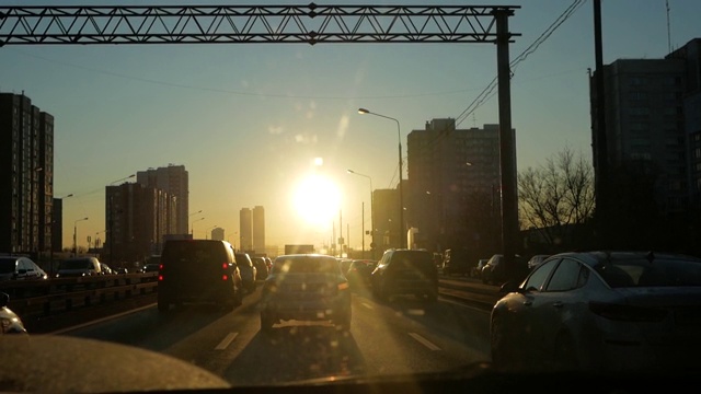 在日落时分开车上路。驾驶汽车向明亮的风景，阳光愉快地照耀在道路上。驾驶汽车旅行的司机。享受日落的天空。自由激励。慢动作视频下载