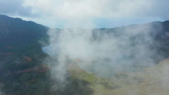 在绿色的死火山火山口中间的浅湖被云朵覆盖。亚速尔群岛科沃的航拍视频素材