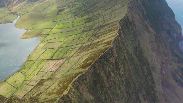 沿着悬崖飞。科沃火山巨大的破火山口的绿色斜坡。亚速尔群岛的航拍视频素材