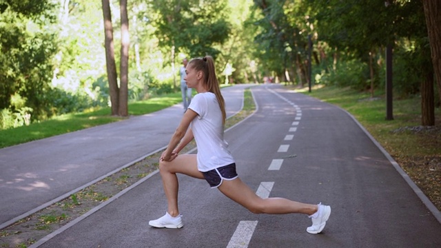 女人跑步伸展腿运动前夏天公园早上视频素材