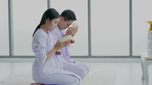 亚洲女人和男人穿着白色衣服祈祷和冥想白色背景应付空间。新常态生活理念。视频下载