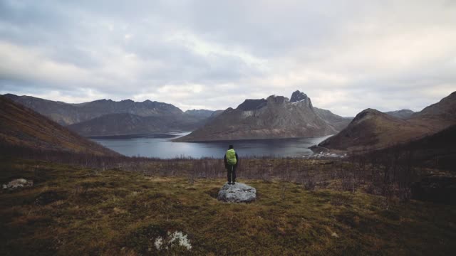 徒步旅行者站在岩石上看峡湾和山脉视频素材