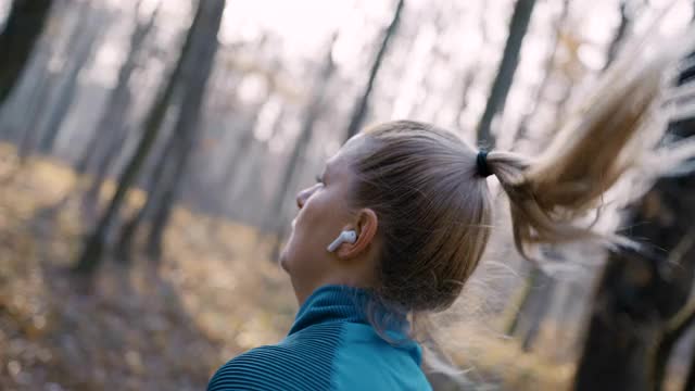 女人听着音乐慢跑穿过秋天的森林视频素材