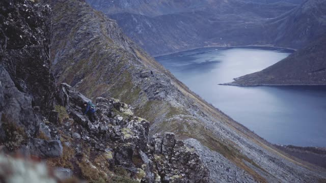 在峡湾上陡峭的山上的徒步旅行者视频素材